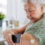 A senior woman uses her smartphone to check her glucose monitor, a tool that can be extremely helpful for diabetes care.
