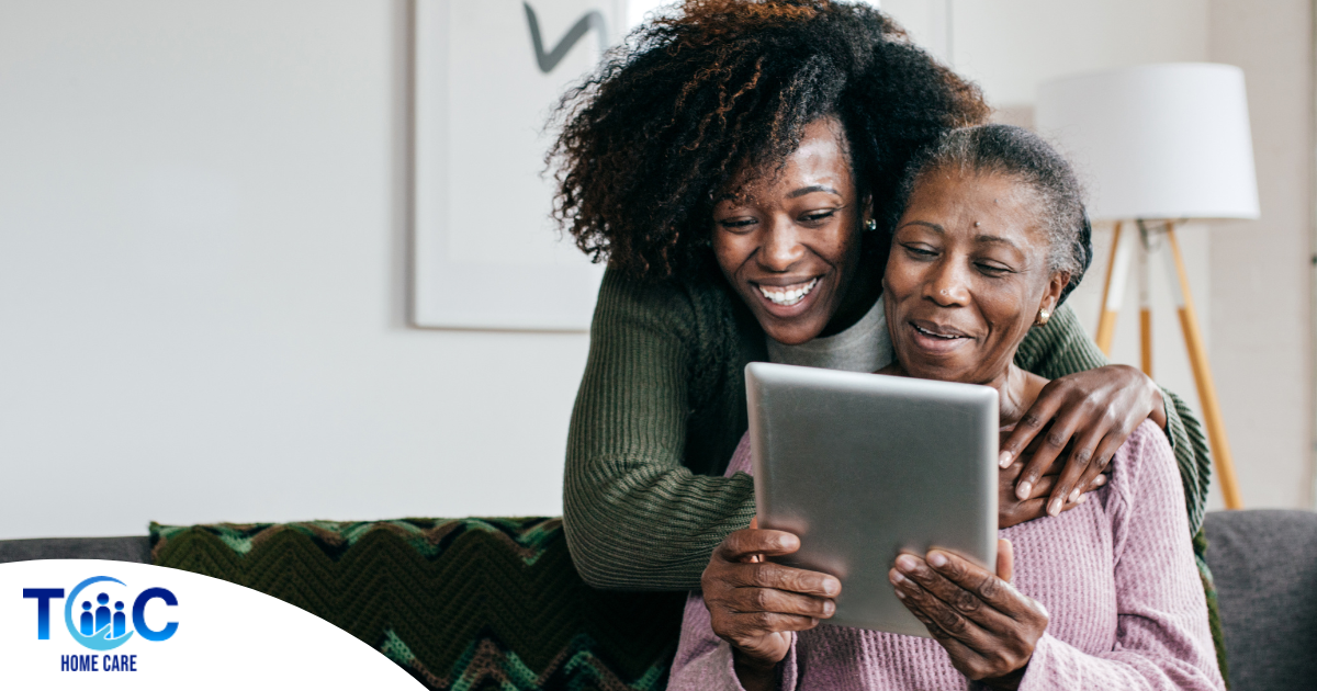 A caregiver helps a senior with her tablet, representing the rise of technology in home care.