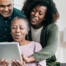 A daughter looks at a tablet with her older parents, representing technology and how ti can help with aging in place.