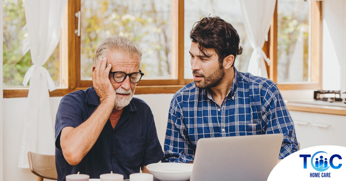A man looks at a computer with his father who is confused, representing one of the early signs of dementia.