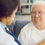 A doctor examines an older man with a stethoscope, representing pneumonia in elderly adults.