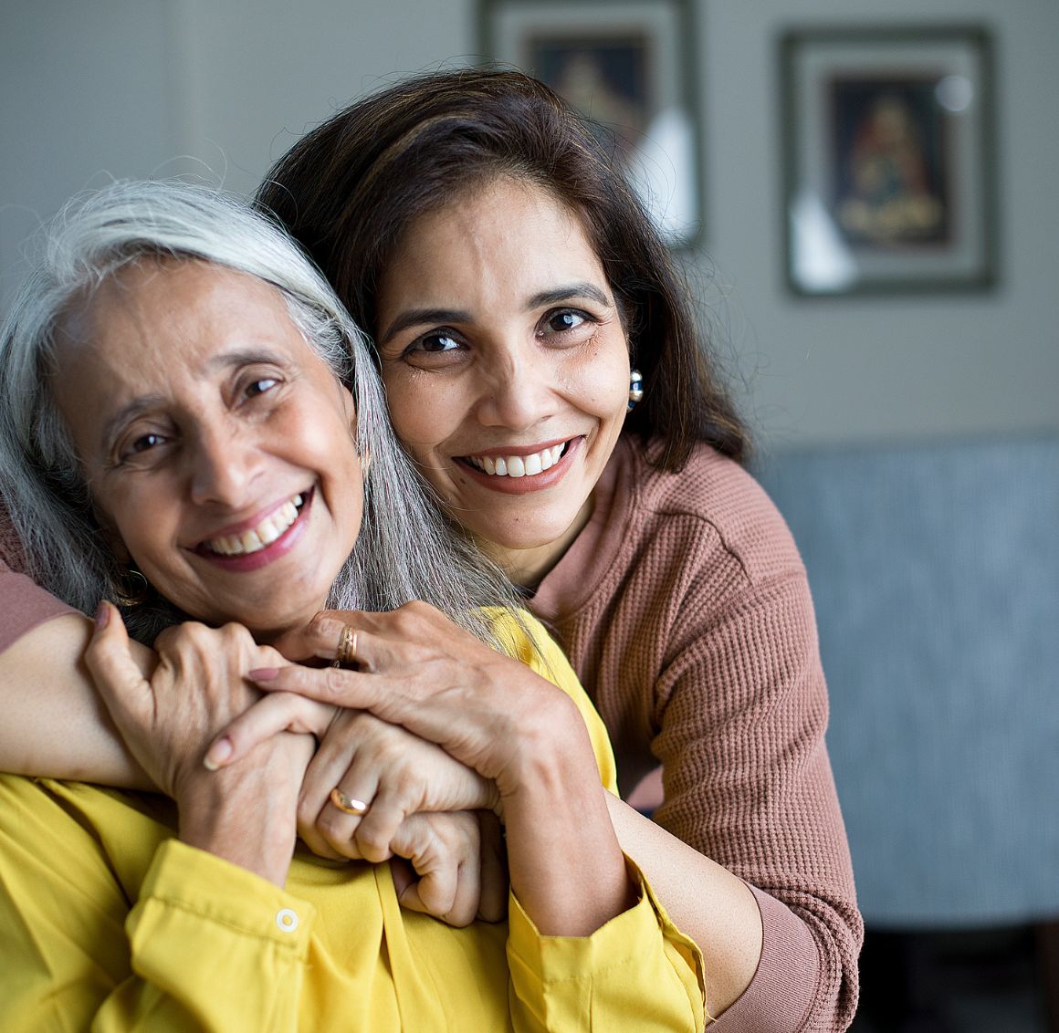 Compassionate caregiver embracing and smiling with a senior woman receiving Personal Care in Pasadena at home.